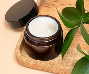 Open jar of beauty peptide cream with green leaves for skin rejuvenation and anti-aging care