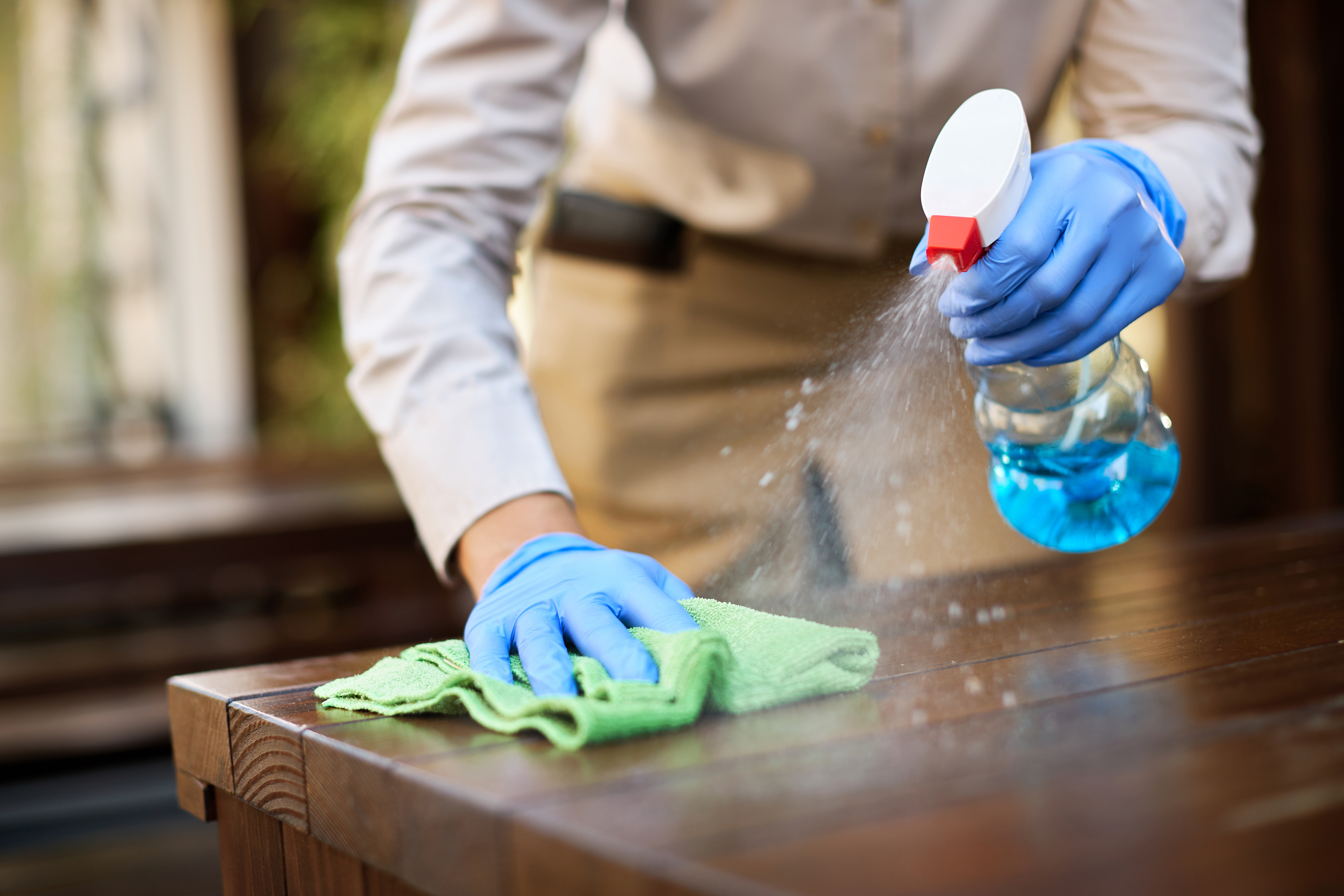 Cleaning agent being sprayed and wiped on a surface for removing contaminants
